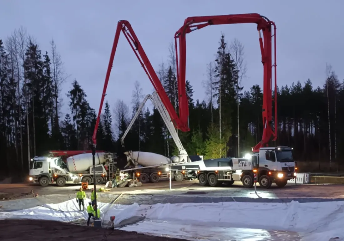 Betonipumppu ja säiliöauto valavat anturaa 47-metrisellä puomilla hämärässä